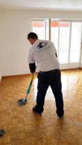 Home All In One Mitarbeiter an der Bodenreinigung in einer Wohnung mit Seifenlauge und Wischmopp.